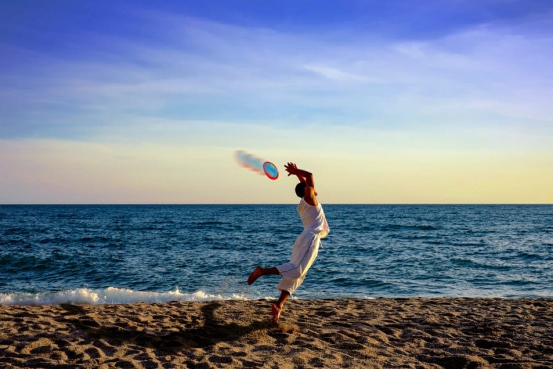 Persona jugando al frisbee en la playa